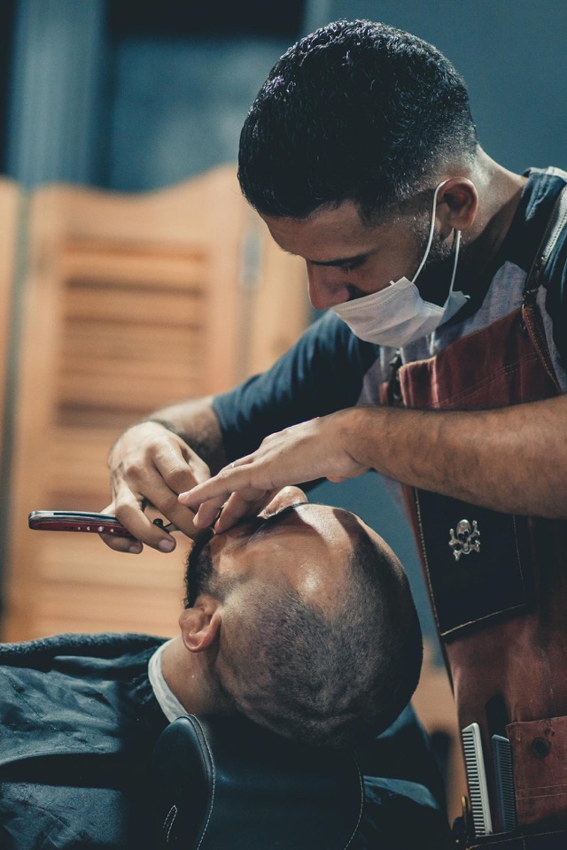 Barber shaping and trimming a client's beard